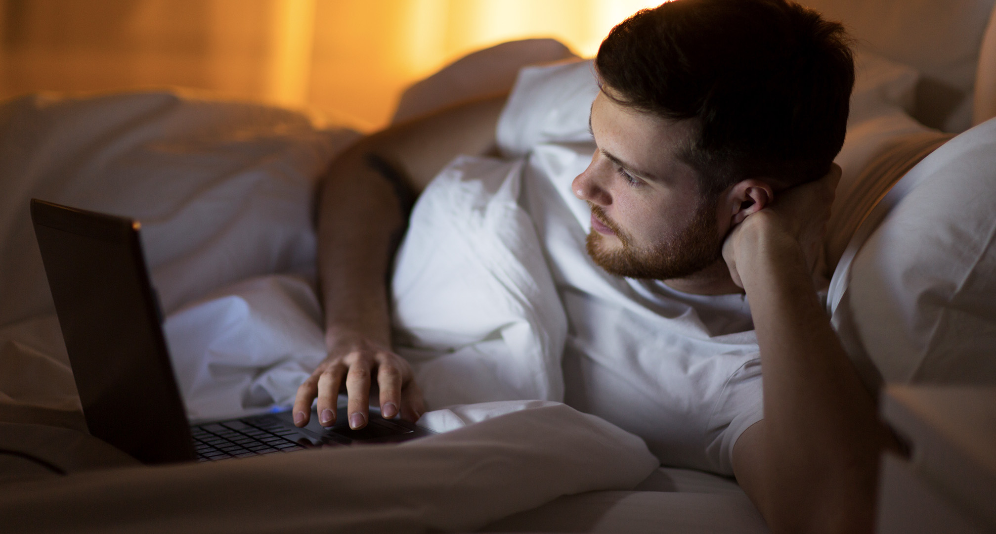 persona che utilizza il computer portatile dal letto durante la notte