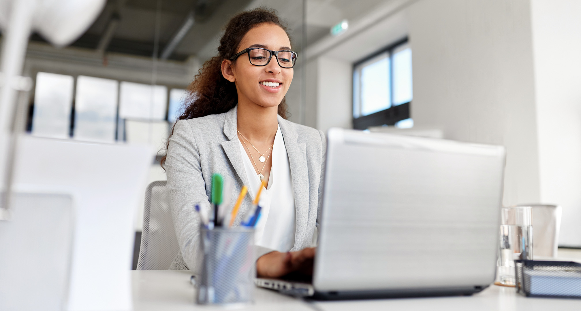 persona che indossa occhiali e utilizza un computer portatile in ufficio